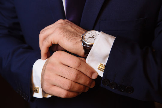 Mans hands with cufflinks and clocks. Elegant gentleman clother