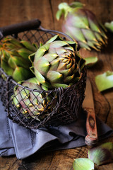 Sardinian thorny artichokes in a wire basket on dark rustic wooden background