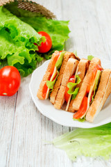 
breakfast or lunch , sandwiches with cheese , sausage , tomato, lettuce and mayonnaise on a wooden background