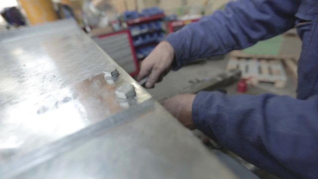 Ouvrier qui sert des boulons sur une plaque de m&eacute;tal