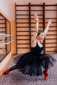 Young Smiling Ballerina Wearing black Tutu Doing exercise in training  hall. Series of photo.