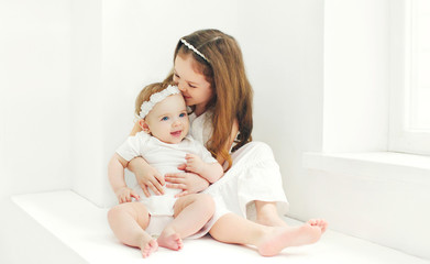 Happy two sisters children playing together at home in white roo
