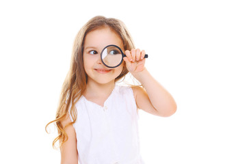 Little girl child looking through a magnifying glass on white ba