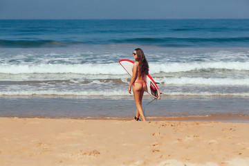  surfer girl in bikini with white surfboard on a beach go to the