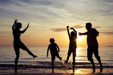 Fototapeta na wymiar Silhouette of happy family who playing on the beach at the sunse