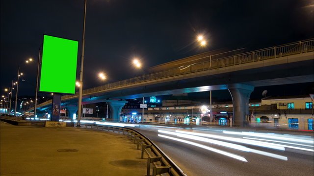 Time lapse: Billboard Green Screen With City Night Traffic Light Trails Background Time-lapse of Empty billboard with Chroma Key Green Screen at Night City
