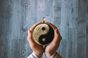 Girl holding a coffee cup with ying and yang symbol.