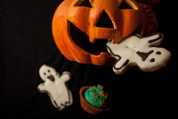Zucca di Halloween con i biscotti a forma di un fantasma in bocca, su uno sfondo nero e la dolcezza di sfocatura.