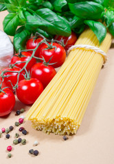 Raw pasta and ingredients for pasta with tomatoes and basil.