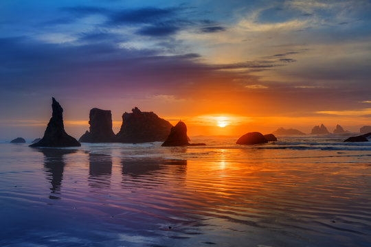 Sunset at Bandon Beach over the Pacific ocean with reflections on wet sand, Bandon, Oregon