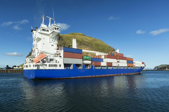 Cargo ship carrying freight containers in the harbor on the isla