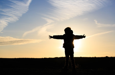 Fototapeta na wymiar Silhouette of happy little boy travel at sunset