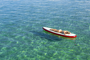 Woman relaxing over a paddle surfboard