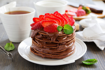 Chocolate pancakes with chocolate cream and strawberries.