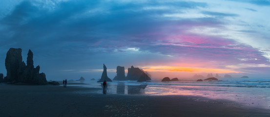A photographers shooting sunset over the stacks at Bandon Beach with reflections on wet sand, Bandon, Oregon © aiisha