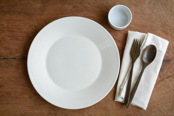 Empty dish with wooden spoon and fork on old wooden background