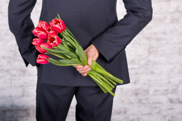 Smiling businessman holding flowers  over white background. Bouq