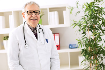 Smiling happy senior doctor in office