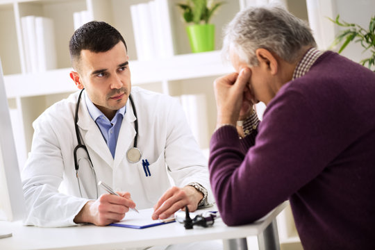 Young doctor carefully listening patient about his pains