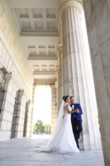 Beautiful bridal couple embracing near columns