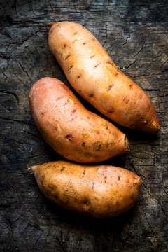 Raw sweet potatoes on wooden background 
