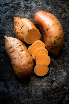 Raw sweet potatoes on wooden background 