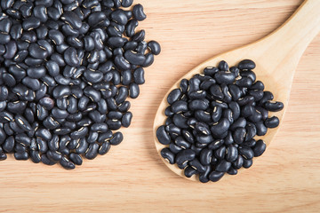 scoop of black bean and a pile of black bean on the wood backgro