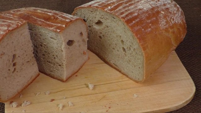 Cut loaf of fresh bread on burlap 
