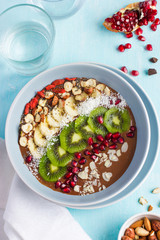 bowl of chocolate smoothie  with fruits nuts on blue background