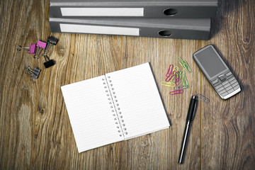 View Of An Office Desk With Gray Ring Binders, Cell Phone, Notepad  And Pen. 