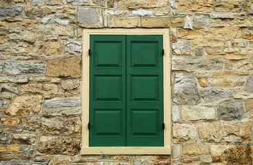 Fototapeta na wymiar Closed green shutters on a stone wall