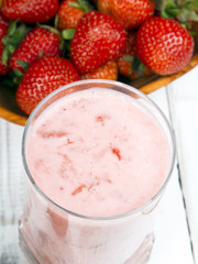 Fresh organic strawberries in bowl on white wooden background