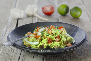 schwarze schale mit Guacamole und zutaten