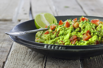 schwarze schale mit Guacamole nud limette
