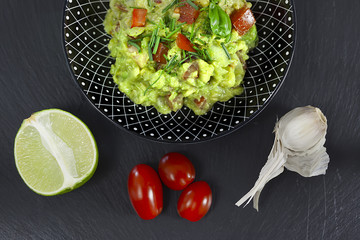 guacamole in einer schwarzen schale mit zutaten