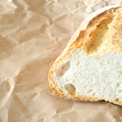 filone di pane italiano, tagliato per mettere in evidenza la mollica,  su carta  marrone, luce solare, spazio per testo, formato quadrato