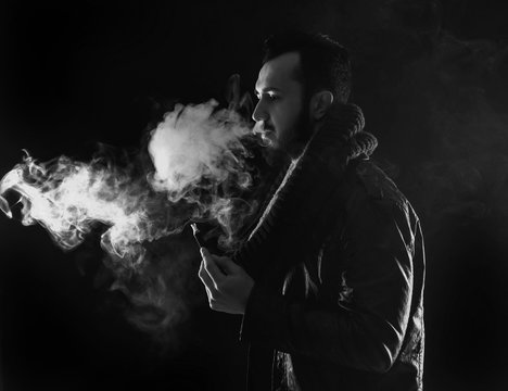 bearded stylish man holding and smoking electronic cigarette