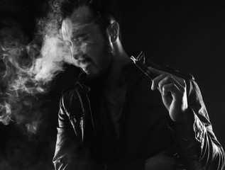 bearded stylish man holding and smoking electronic cigarette