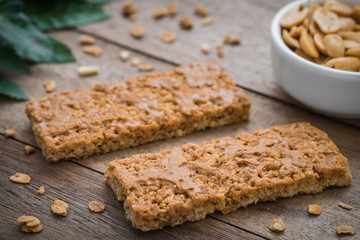 Granola bars on wooden table and peanuts in bowl