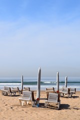 Sonnenliegen, Sonnenschirme und Fußspuren an einem leeren Strand