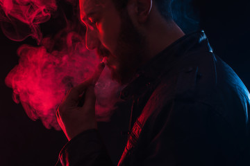 bearded stylish man holding and smoking electronic cigarette