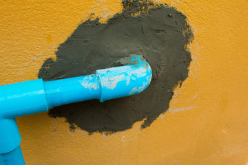 Blue Plastic Water Pipe on the Rough Cement Wall