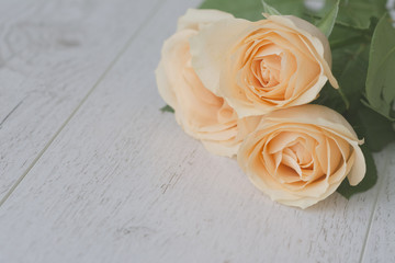 Close up background with yellow roses over white wooden table. Top view with copy space