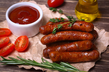 roasted sausages with tomato sauce and herbs on a wooden background
