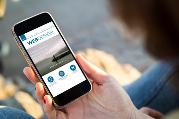 woman sitting in the street holding her smartphone showing web d