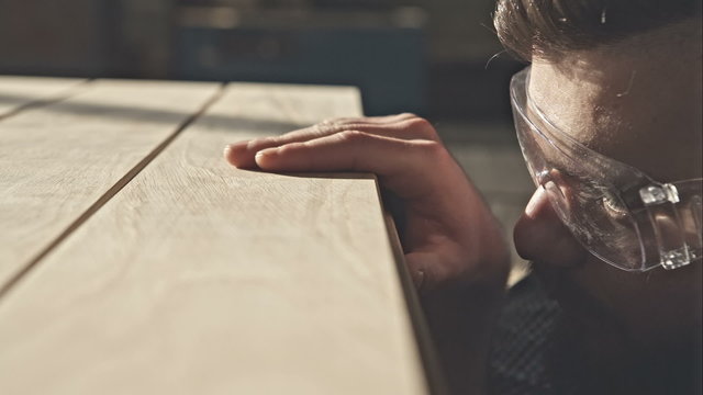 Carpenter checks the quality sanding wooden board. RAW video record.