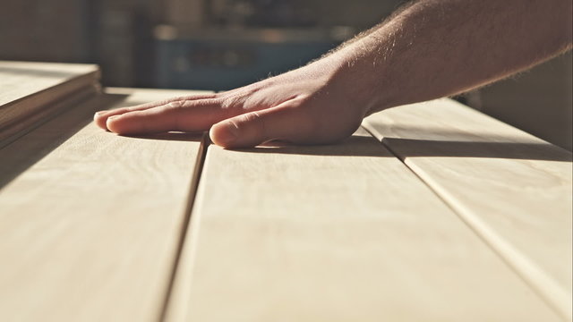 The young master hand touches the wooden boards in the sun. RAW video record.