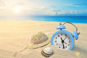 Alarm clock and hat on the seashore - obrazy, fototapety, plakaty