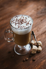 Cappuccino coffee in a glass on a brown wooden table