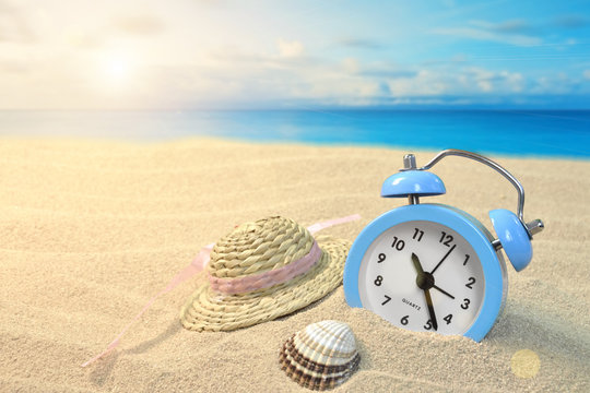 Alarm clock and hat on the seashore